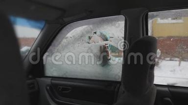 清理汽车侧窗积雪.. 一个孩子`手清洁汽车玻璃。 男孩笑得甜甜的